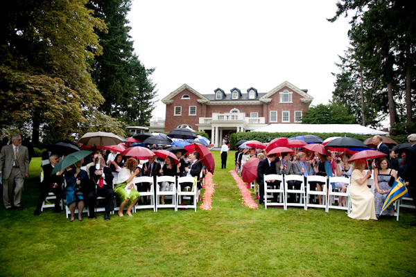 outdoor ceremony with guests holding umbrellas - photo by Seattle based wedding photographers La Vie Photography